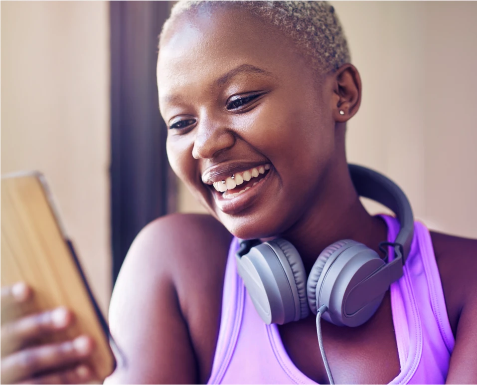 Mulher sorridente usando o celular para consultar empréstimo consignado com as melhores taxas