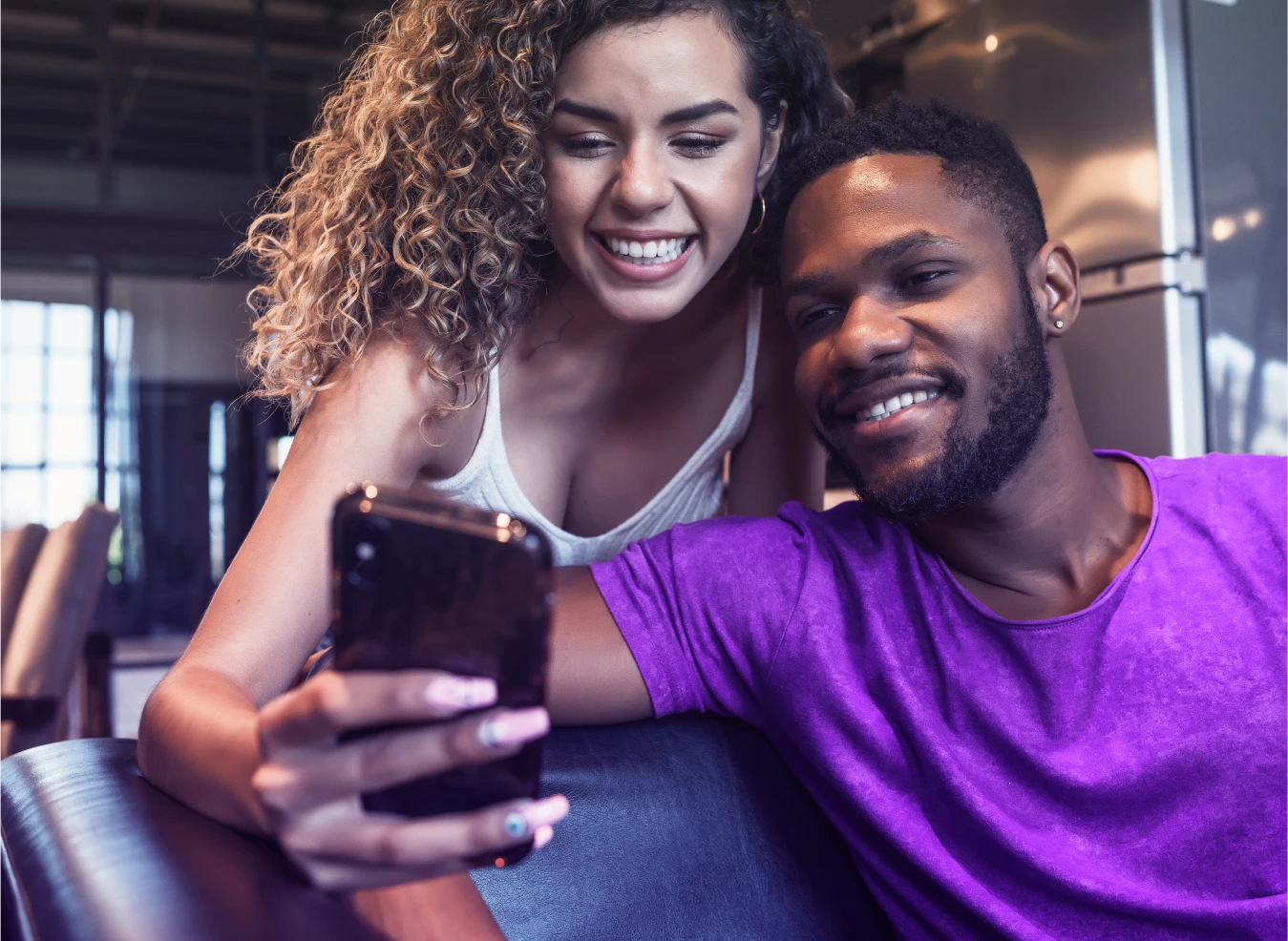 Casal sorridente olhando o celular com expressão de tranquilidade, representando segurança na proteção de dados